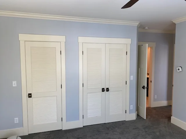 Blue residential bedroom with white louvered closet doors