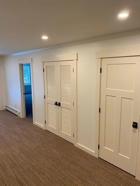 White residential hallway with louvered closet doors